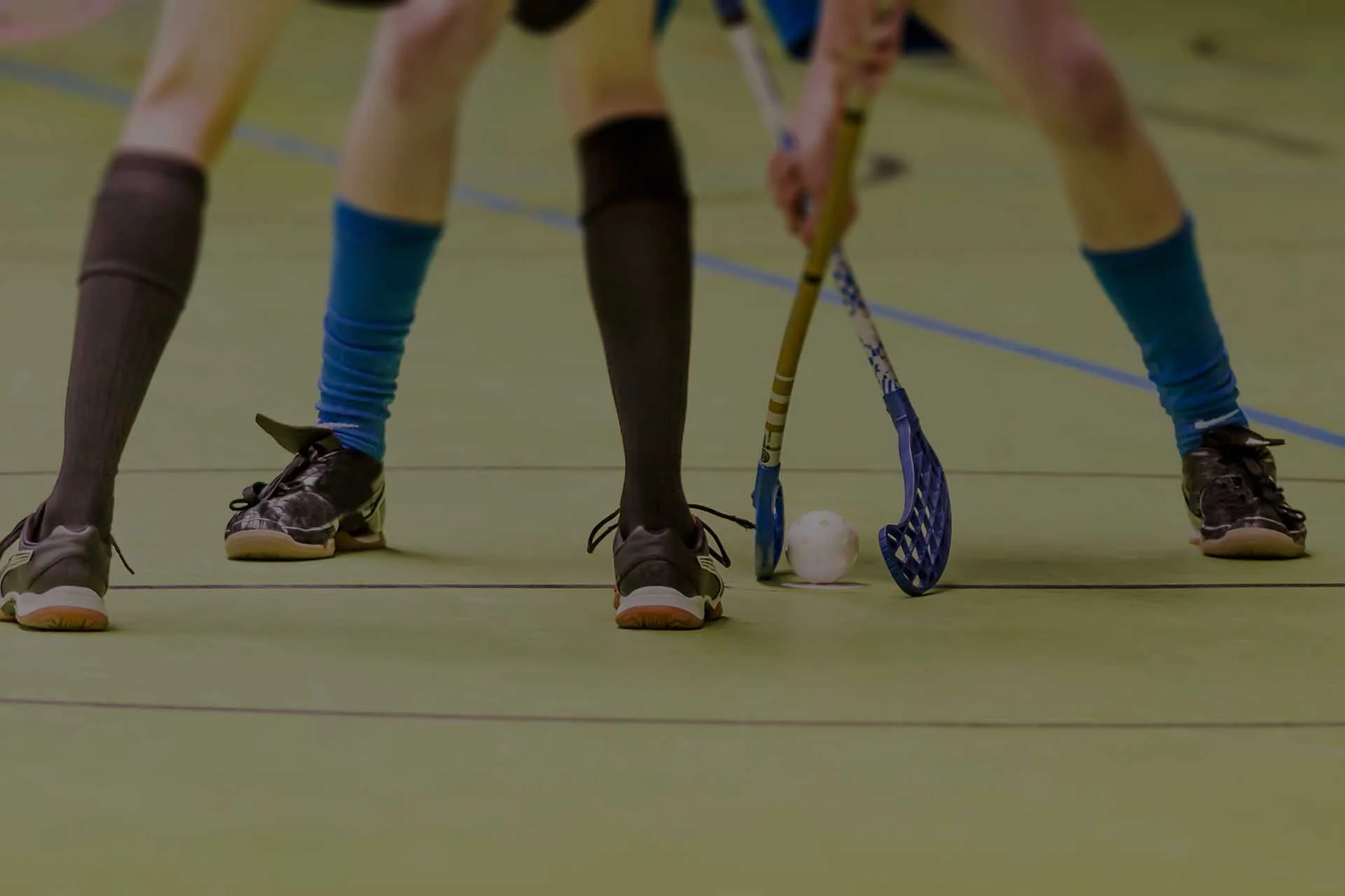 Innebandyspelare med klubbor på hallgolvet
